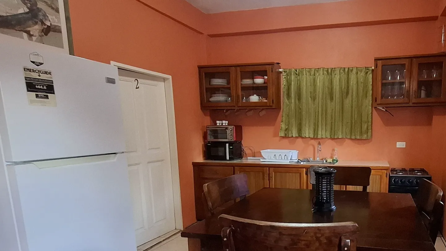 The apartment's kitchen and dining table, with a full fridge, gas cooker and glass-front cabinets