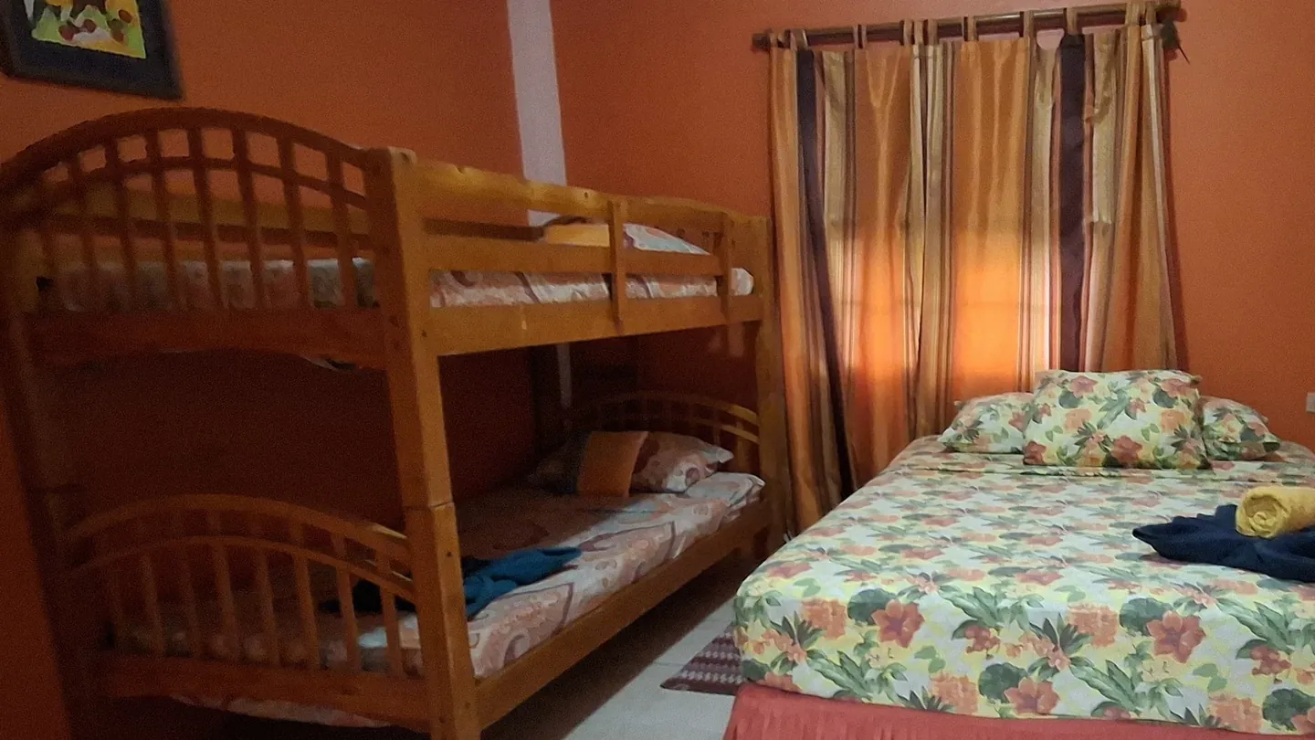The apartment's orange bedroom, a queen bed beside a twin-over-double bunk