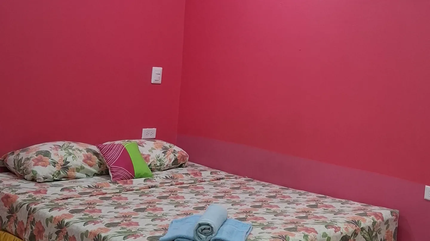 The Mango Room's queen bed against pink walls