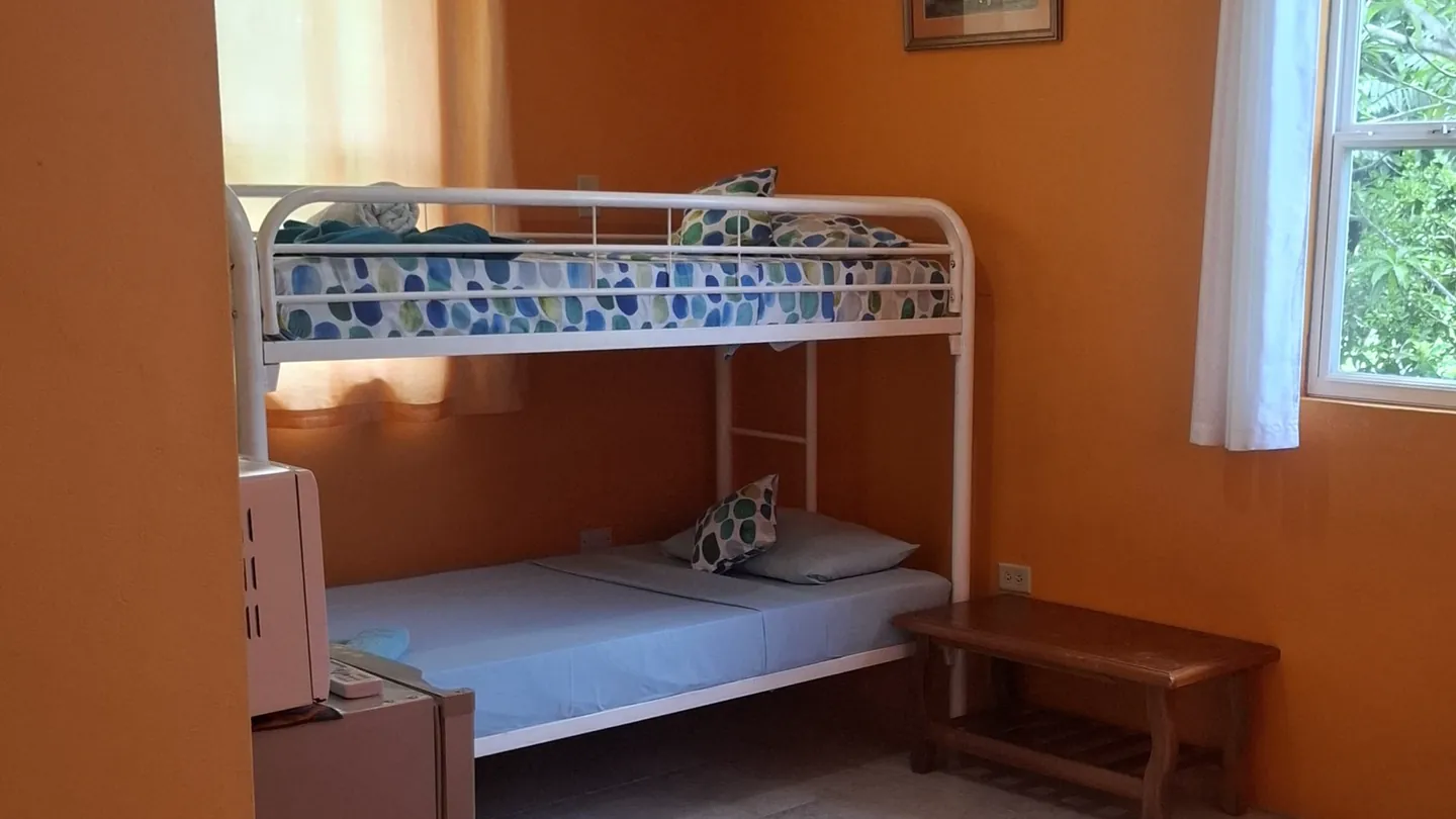 The room's twin bunk and the fridge with a microwave on top