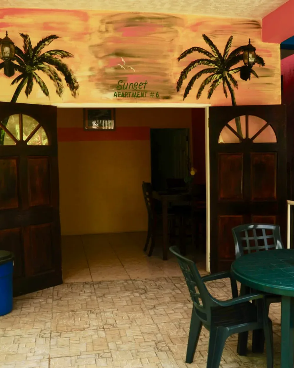 The guest house entrance, palms painted across the wall and the dining tables just inside