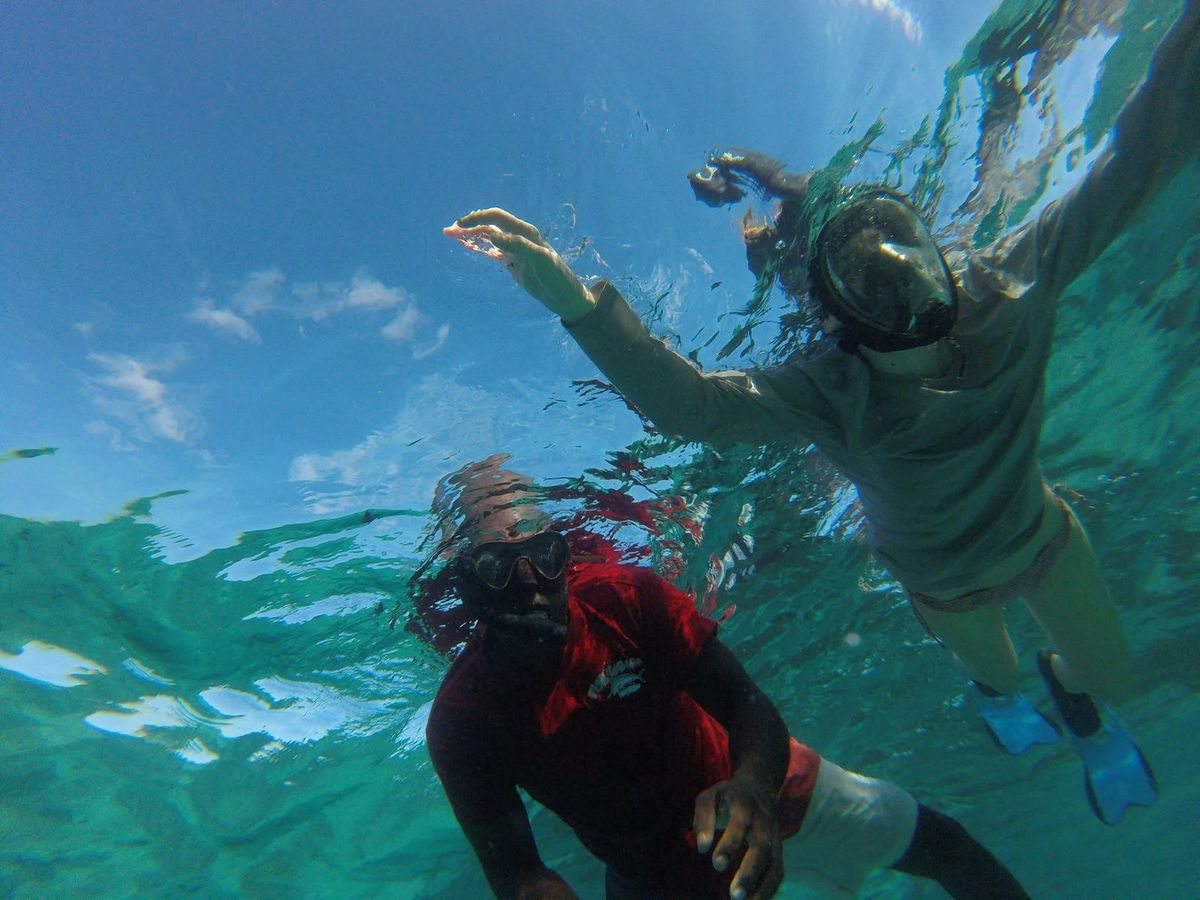 The guide and a guest snorkelling in clear turquoise water, selfie-stick shot